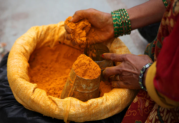 Turmeric powder being measured from a sack at a market in Nepal