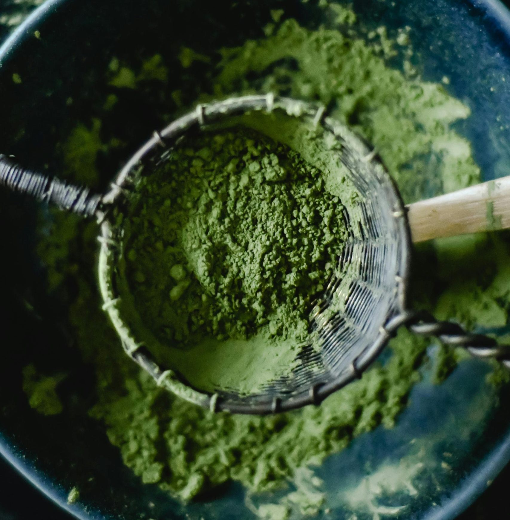a person processing filtering moringa powder using metallic tool